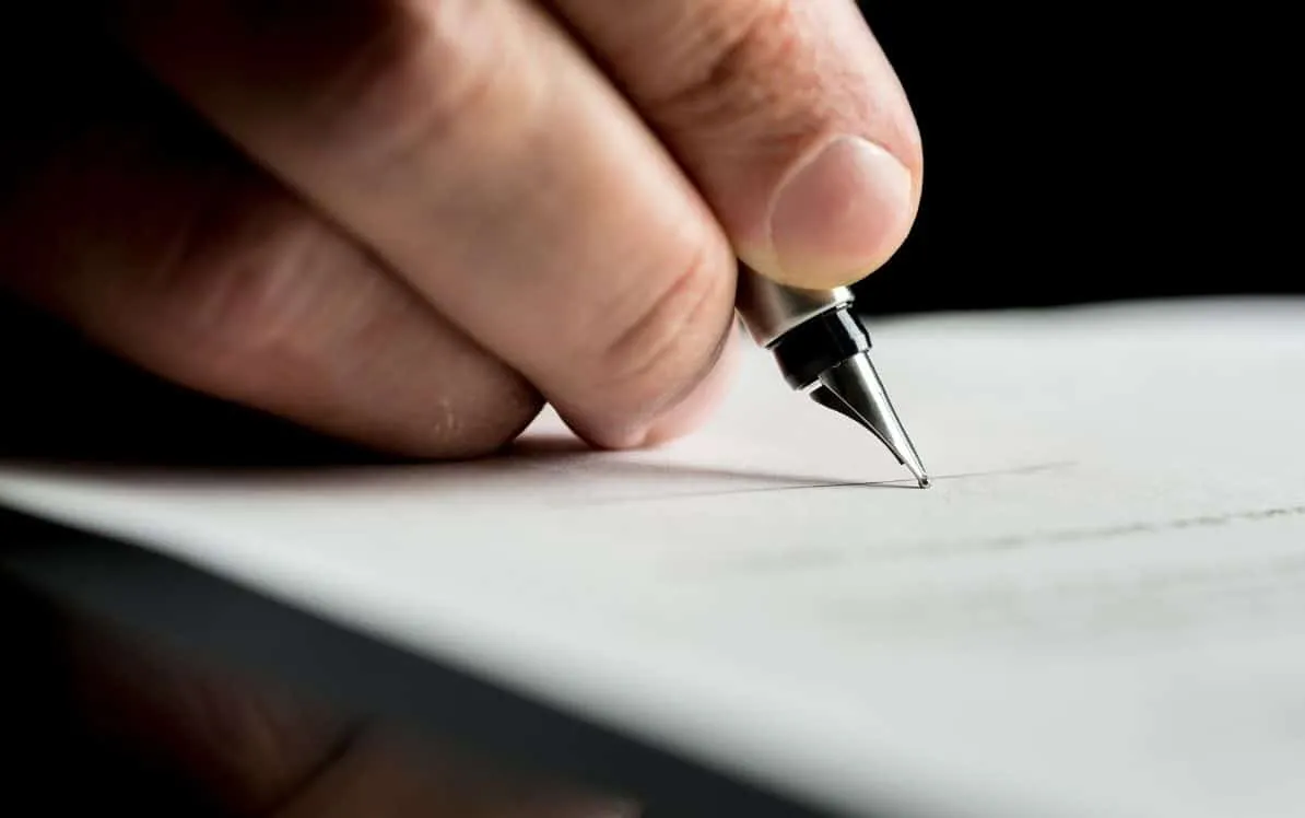 Hand holding a pen writing on paper.